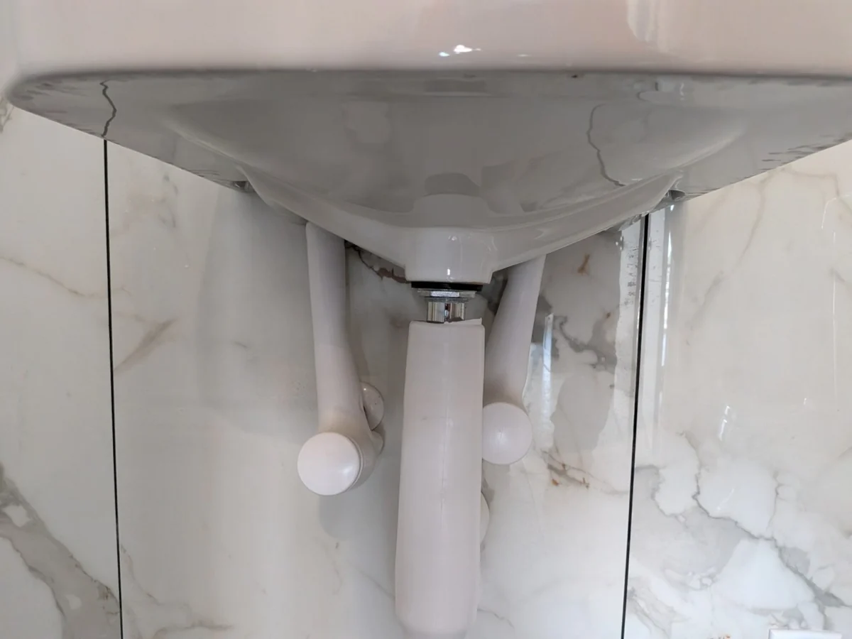 White drain trap and piping beneath a bathroom sink